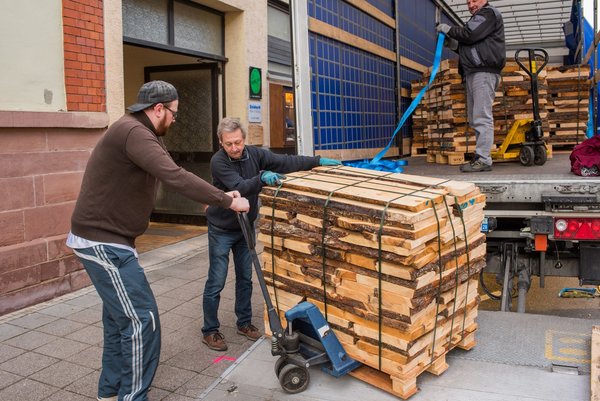 Zwei Männer laden Zirbenholz von LKW